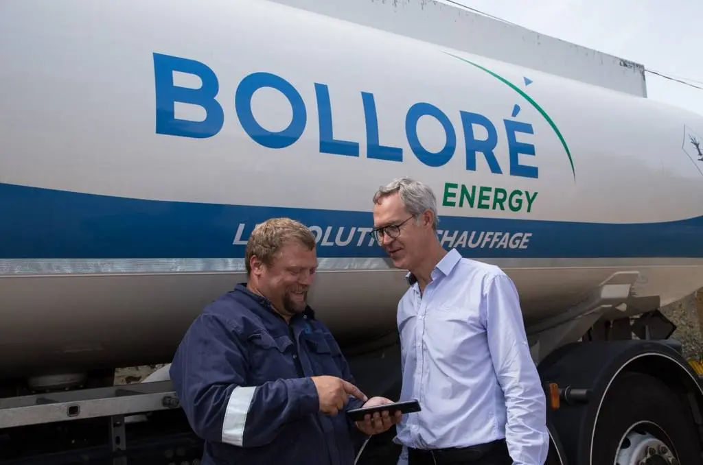 Technicien Bolloré Energy échangeant avec un client devant un véhicule de livraison d’énergie