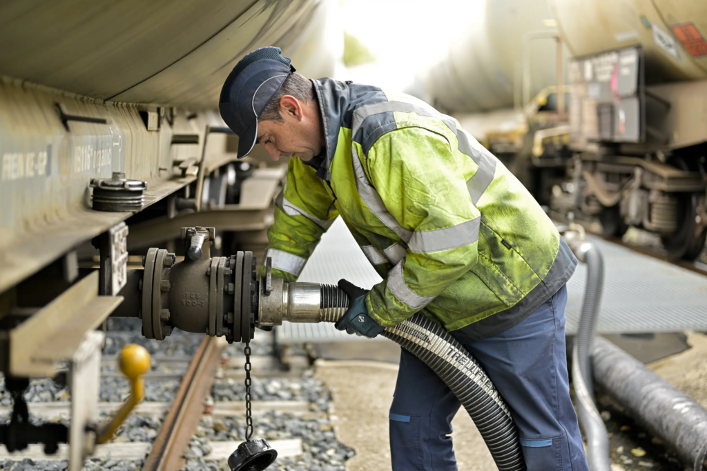 Technicien Bolloré Energy raccordant un flexible de transfert sur un wagon-citerne