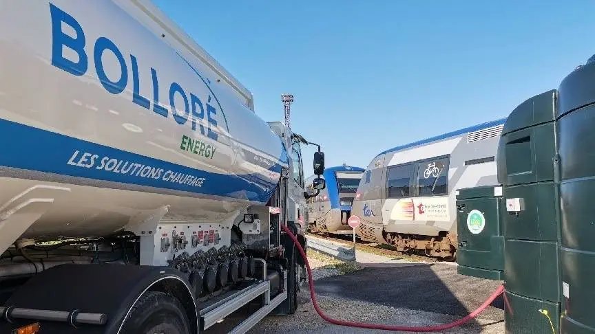 Camion-citerne Bolloré Energy alimentant un train stationné sur une infrastructure ferroviaire